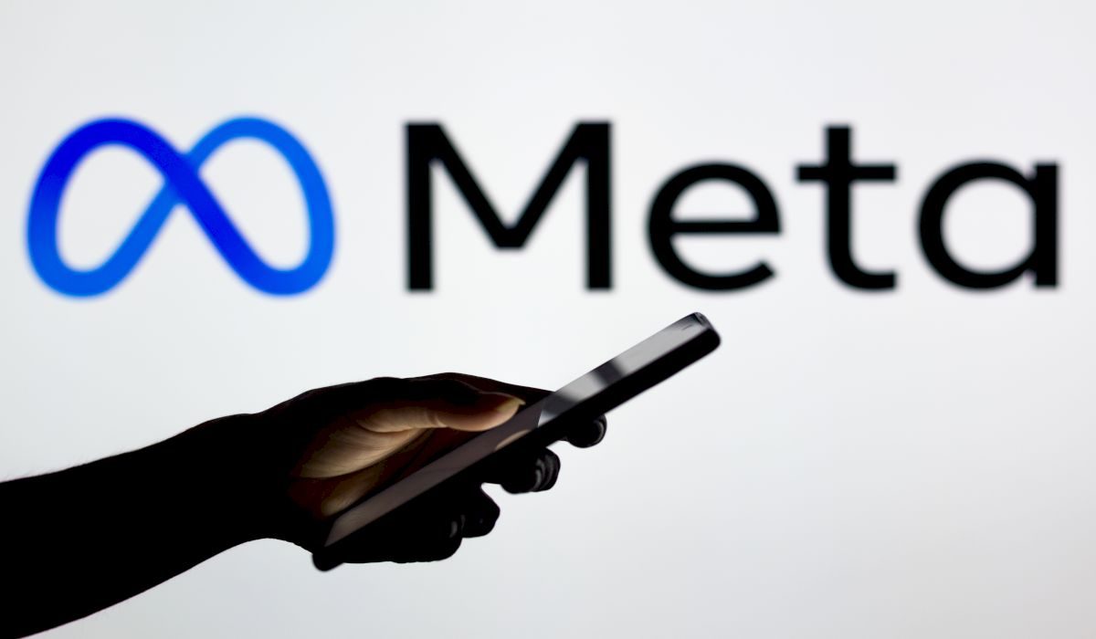 March 16, 2022, Brazil. In this photo illustration the Meta Platforms logo seen in the background of a silhouette woman holding a mobile phone.
